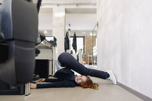 Geschäftsfrau auf dem Boden liegend im Büro beim Sport - KNSF06647