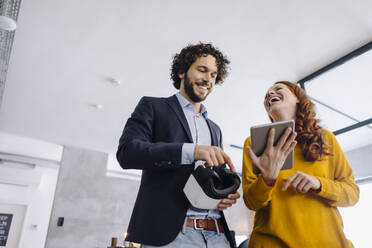 Happy businessman and businesswoman with VR glasses and tablet in office - KNSF06653