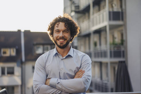 Portrait of smiling businessman on roof terrace - KNSF06658