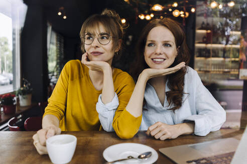 Two female friends with laptop in a cafe - KNSF06667