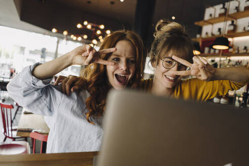 Two playful female friends with laptop in a cafe - KNSF06671