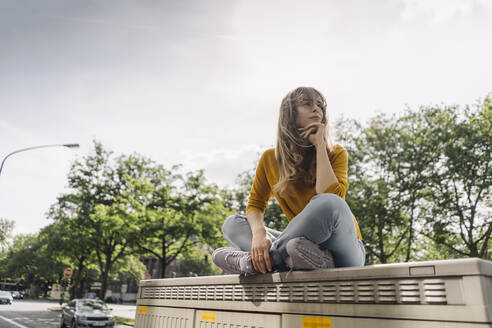 Young woman sitting on a box in the city - KNSF06672