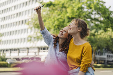 Two happy female friends taking a selfie in the city - KNSF06689