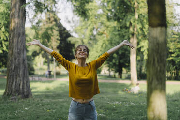 Young woman in a park with outstretched arms - KNSF06698