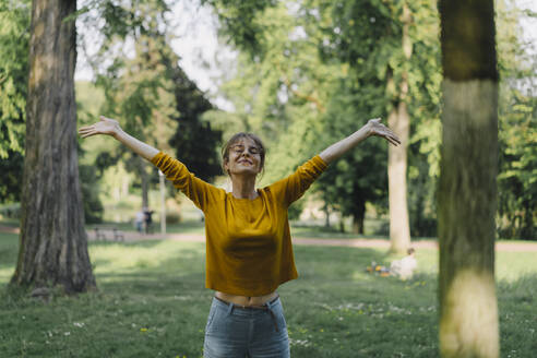 Young woman in a park with outstretched arms - KNSF06698