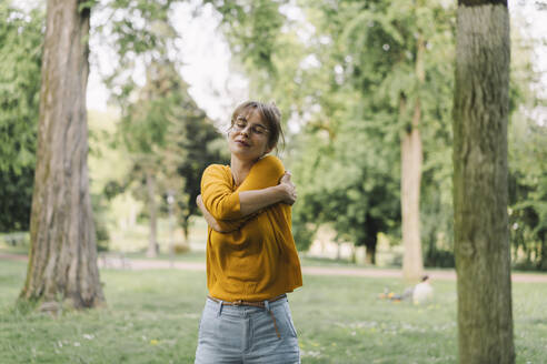 Young woman in a park hugging herself - KNSF06699