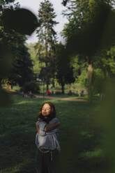 Redheaded woman in a park hugging herself - KNSF06703