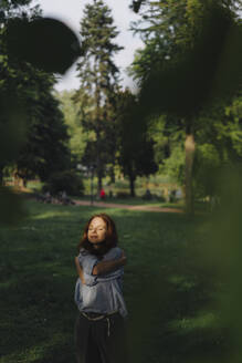 Rothaarige Frau in einem Park, die sich umarmt - KNSF06703