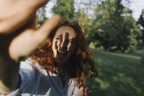 Happy redheaded woman meeting a friend in a park - KNSF06705