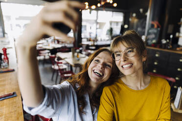 Zwei glückliche Freundinnen machen ein Selfie in einem Restaurant - KNSF06707