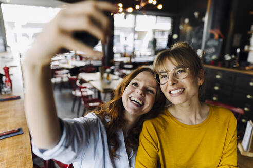 Zwei glückliche Freundinnen machen ein Selfie in einem Restaurant - KNSF06707