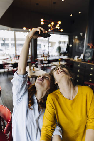 Zwei glückliche Freundinnen machen ein Selfie in einem Restaurant, lizenzfreies Stockfoto
