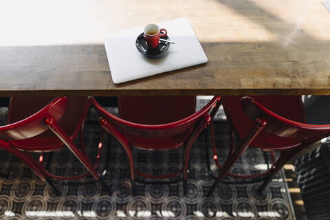 Laptop und Tasse Kaffee auf einem Tisch in einem Café, lizenzfreies Stockfoto