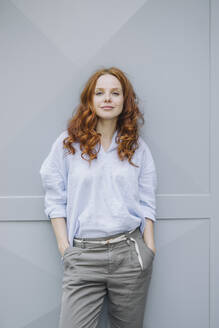 Portrait of beautiful redheaded woman standing at a wall - KNSF06719