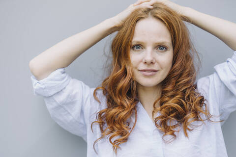 Portrait of beautiful redheaded woman at a wall stock photo