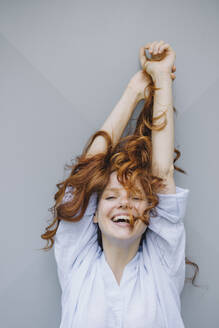 Portrait of happy redheaded woman at a wall - KNSF06722