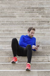 Jogger sitting on steps and using smartphone - JSRF00658