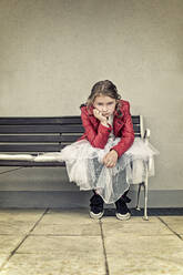 Porträt eines unglücklichen Mädchens in roter Lederjacke und Tutu, das auf einer Bank sitzt - STBF00410