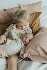 Girl with newborn sibling on bed - JOHF01045