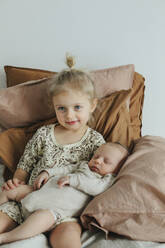 Girl with newborn sibling on bed - JOHF01048