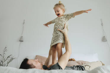 Father playing with daughter on bed - JOHF01123