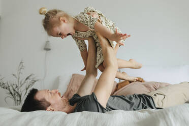 Father playing with daughter on bed - JOHF01124