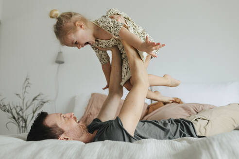 Vater spielt mit Tochter auf dem Bett - JOHF01124