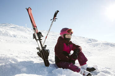 Mädchen mit Skiern in den Bergen sitzend - JOHF01208