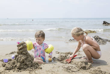 Girl playing in sand by sea - JOHF01279