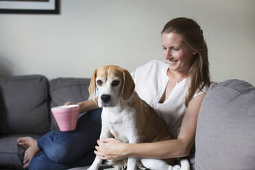 Frau sitzt mit Hund auf dem Sofa - JOHF01348