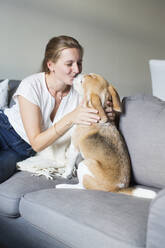 Frau sitzt mit Hund auf dem Sofa - JOHF01355