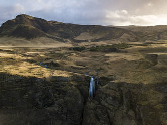 Island, Luftaufnahme eines Wasserfalls, der eine hohe Klippe hinabstürzt - DAMF00076