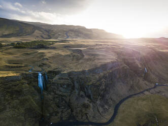 Island, Luftaufnahme eines Wasserfalls, der bei Sonnenuntergang eine hohe Klippe hinabstürzt - DAMF00077