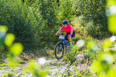 Woman cycling in forest - JOHF01381