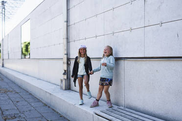 Two girls standing by wall - JOHF01430