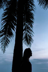 Silhouette of woman contemplating under palm tree - JOHF01447
