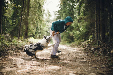 Frau spielt mit Hund im Wald - JOHF01563