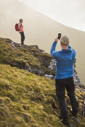 Mann fotografiert Frau beim Wandern - JOHF01659