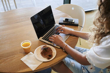 Junge Frau in einem Café mit Laptop beim Frühstück - IGGF01330