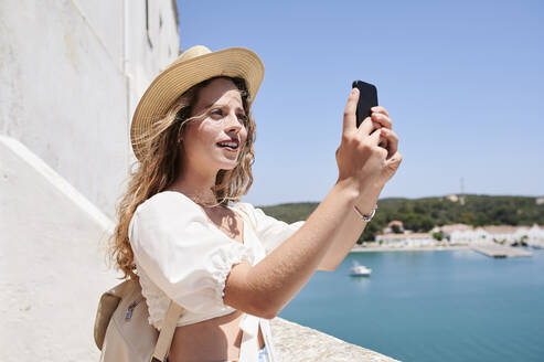 Junge Frau macht ein Selfie an der Küste, Menorca, Spanien - IGGF01344