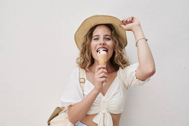 Portrait of happy young woman with hat eating ice cream - IGGF01356