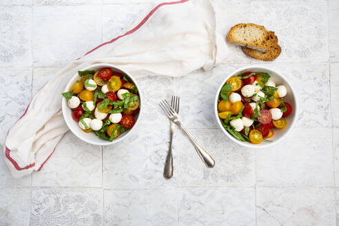 Serviette, Gabeln, Brotscheiben und zwei Schüsseln mit frischem Salat liegen auf dem gekachelten Tisch - LVF08284