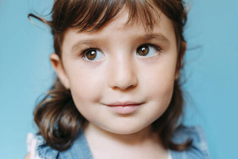 Portrait of cute little girl, blue background stock photo