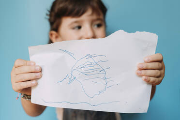 Kleines Mädchen hält eine handgefertigte Zeichnung auf blauem Hintergrund - GEMF03191