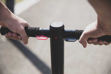 Close-up of hands on handlebar of an e-scooter - MOEF02476