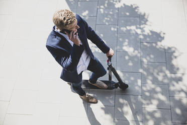 Young man with e-scooter talking on the phone in the city - MOEF02479