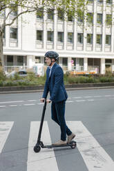 Junger Geschäftsmann fährt E-Roller in der Stadt - MOEF02504