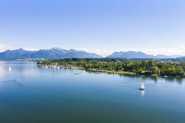 Germany, Bavaria, Prien am Chiemsee, Sailboats sailing near shore of Chiemsee lake with Chiemgau Alps in background - MMAF01147