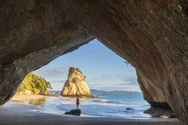 Neuseeland, Nordinsel, Waikato, Silhouette einer Frau, die unter einem natürlichen Bogen in der Cathedral Cove steht - FOF10955