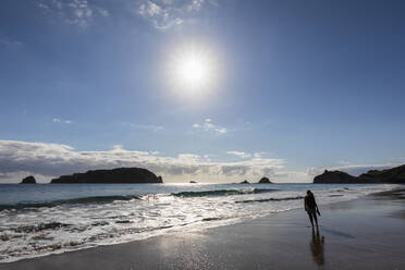 Neuseeland, Nordinsel, Waikato, Sonne scheint über die Silhouette einer allein stehenden Frau am Hahei Beach - FOF10964